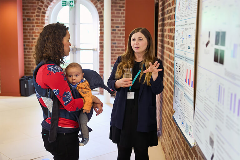 Two female conference participants discussing a scientific poster