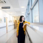 A colour photo of a genetic counsellor standing in a hospital corridor.