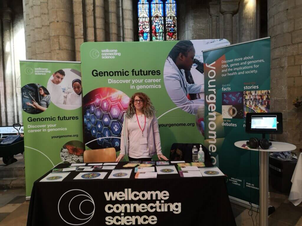 Member of the Wellcome Connecting Science team ready to welcome students to the Genomic Futures careers stand.