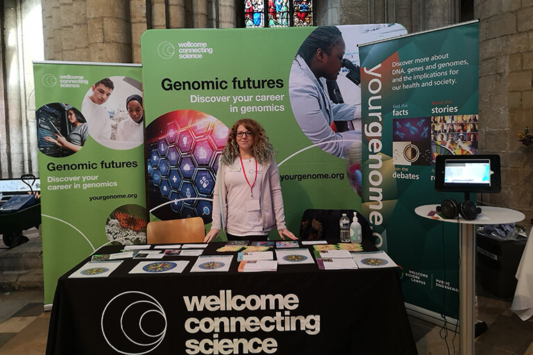 Member of the Wellcome Connecting Science team ready to welcome students to the Genomic Futures careers stand.