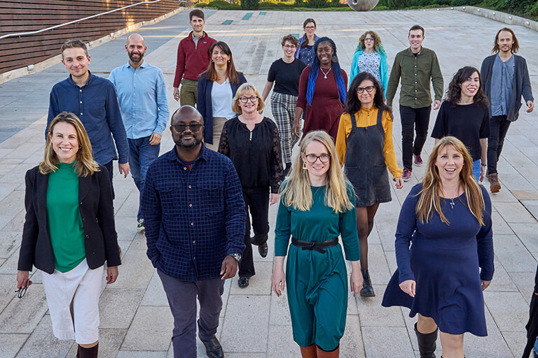 18 members of the Engagement and Society team, walking as a group outside.